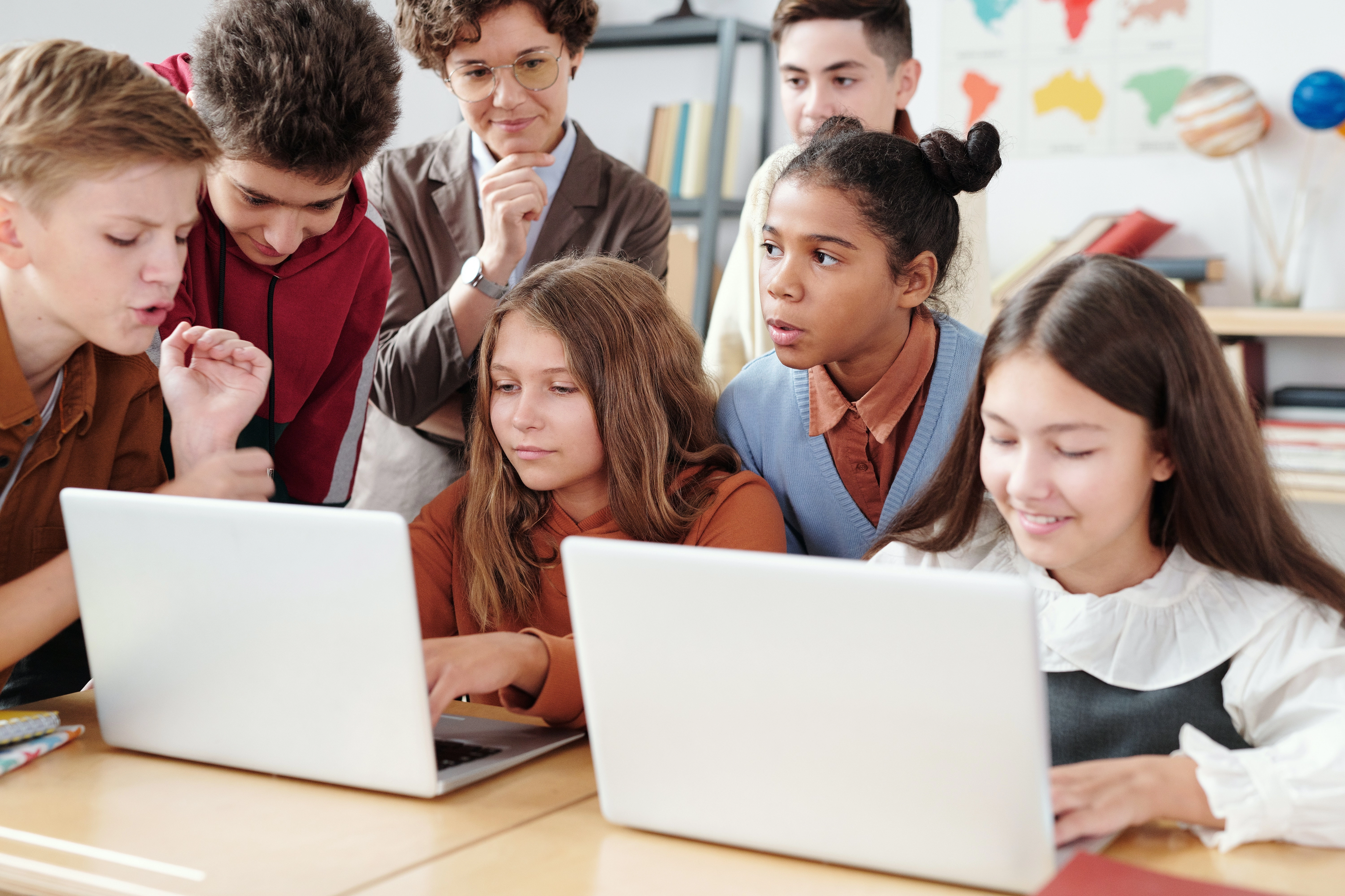 Fotografia de xiquets usant ordinadors portàtils a una aula d'un col·legi en presència d'una mestra